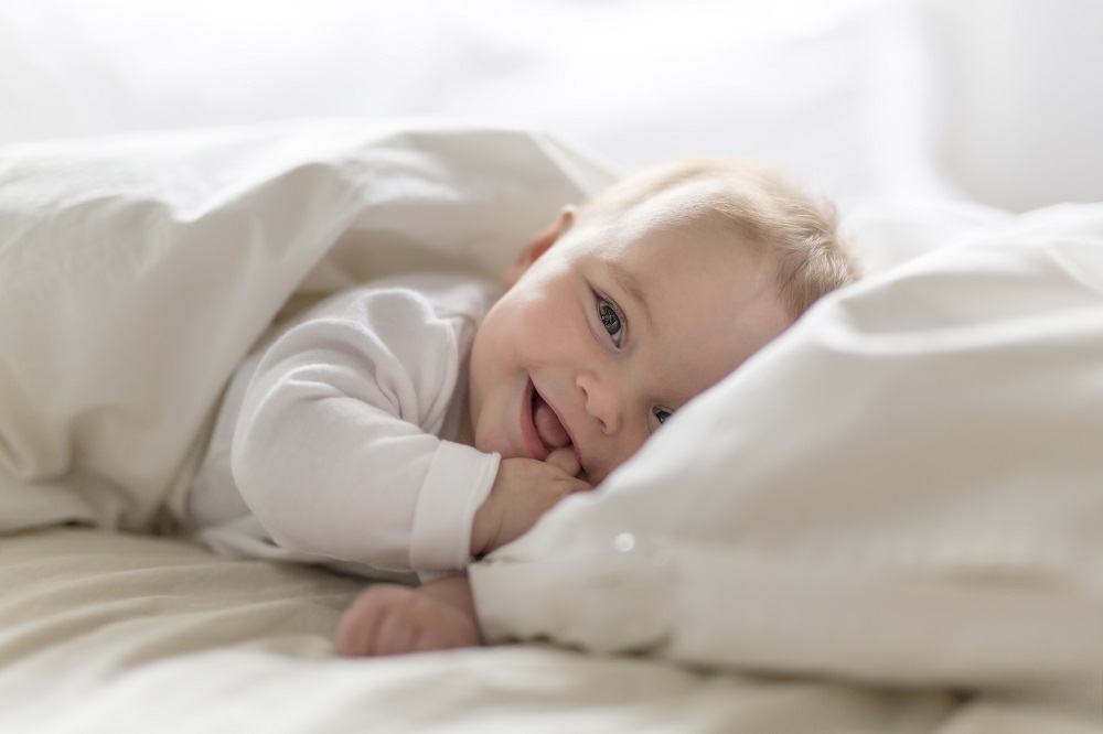 Cute happy 7 month baby girl in diaper lying and playing